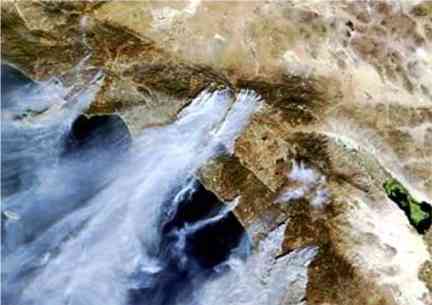 In this satellite image, plumes of smoke caused by wildfires are seen moving off the coast through Southern California on Sunday.